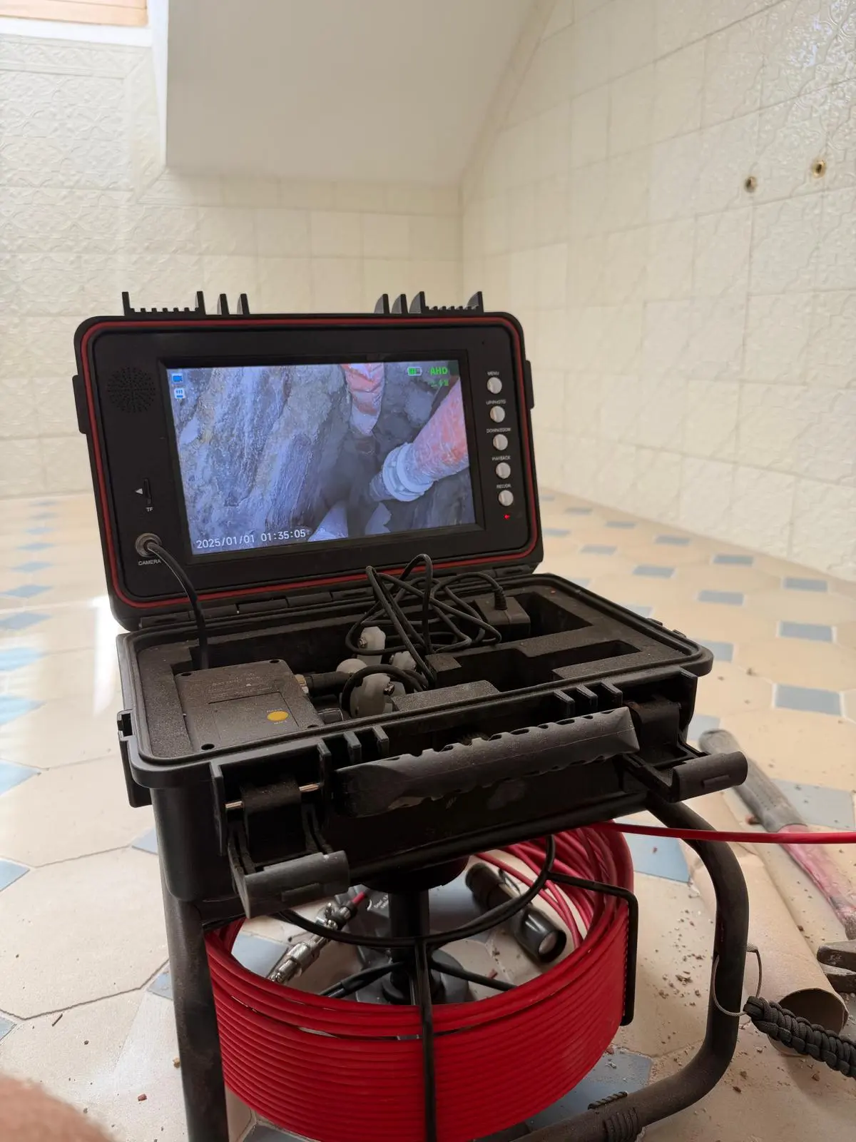 Rohrkamera mit Monitor und rotem Kamerakabel beim Einsatz